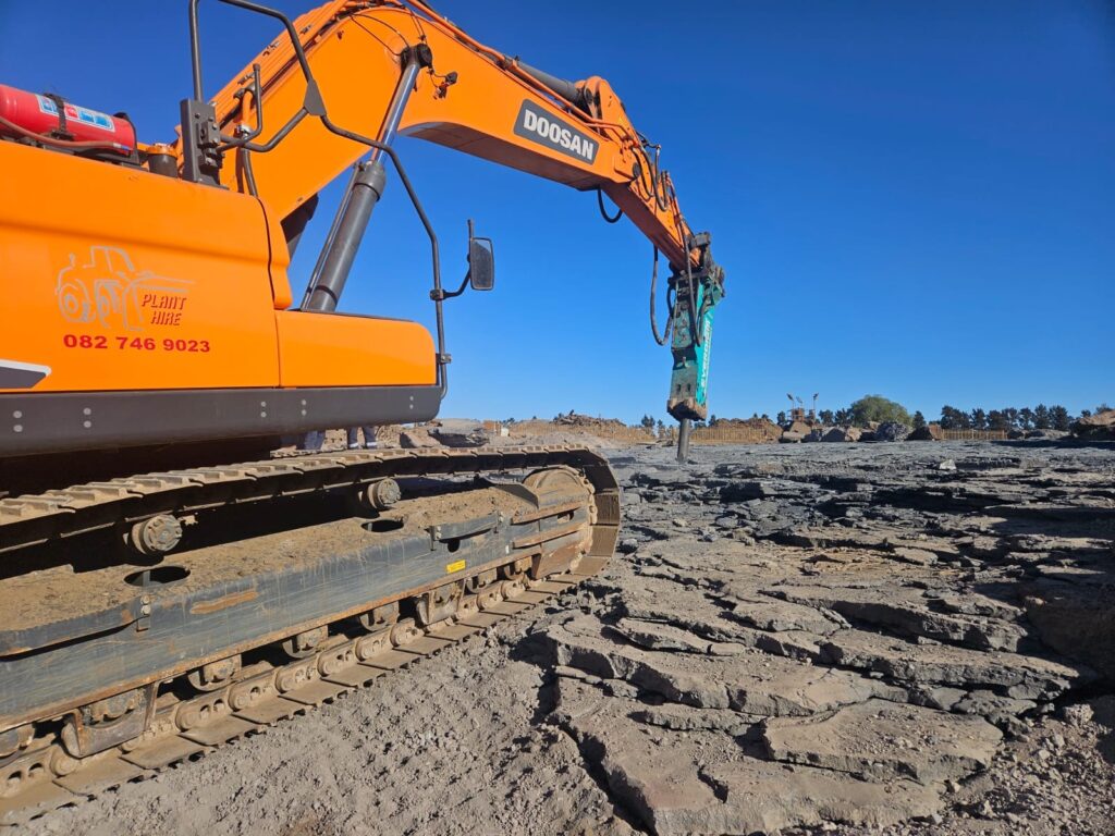 Doosan excavator fitted with a hydraulic rock breaker performing rock excavation on a construction site in South Africa for Plant Hire services.